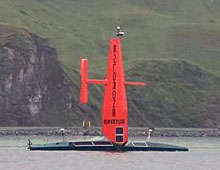 Saildrone in Dutch Harbor, Alaska with soaring green hills in the background.