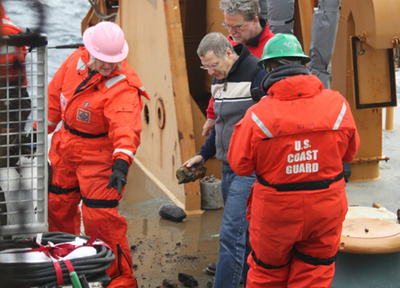 Larry Mayer observes the dredge on Healy's deck with Kelly Brumley and Bernie Coakley.